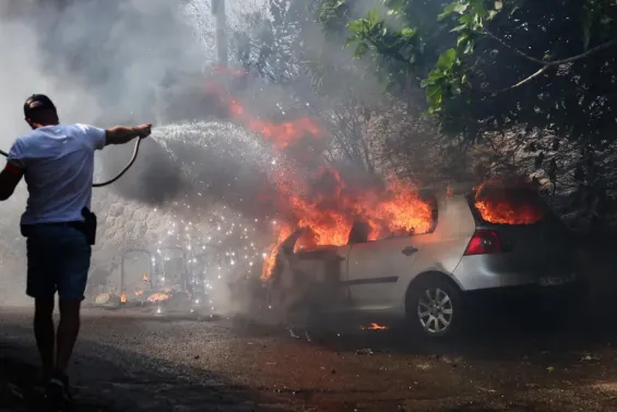 A police officer tries to extinguish a car on fire in L'Estaque, a district of Marseille, on July 8, 2025. © Clement Mahoudeau, AFP