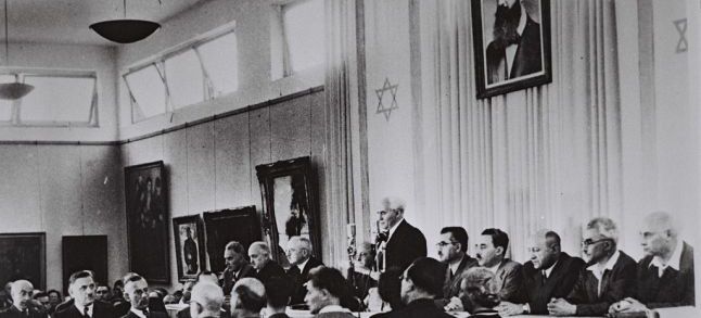 David Ben-Gurion, flanked by the members of his provisional government, reads the Declaration of Independence in the Tel Aviv Museum Hall on May 14, 1948./Ph.  Israel Government Press Office)