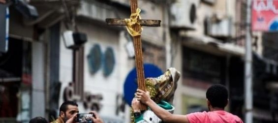 Egyptians holding a cross to condemn the bombing of two coptic churches./Ph. Mohammed El-Shahed- AFP