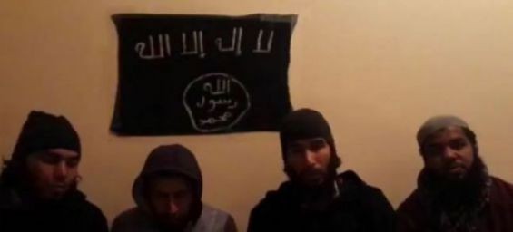 The four suspects seated beneath ISIS flag./Ph. Twitter