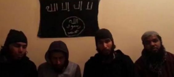 The four suspects seated beneath ISIS flag./Ph. Twitter