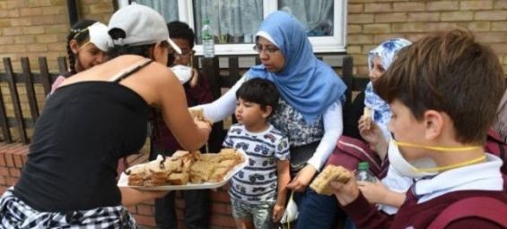 Sandwiches are handed out to local residents close to a fire that has engulfed the 24-storey Grenfell Tower in west London./Ph. VICTORIA JONES/PA