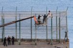 Des migrants subsahariens franchissent la barrière frontalière séparant le Maroc et Melilla