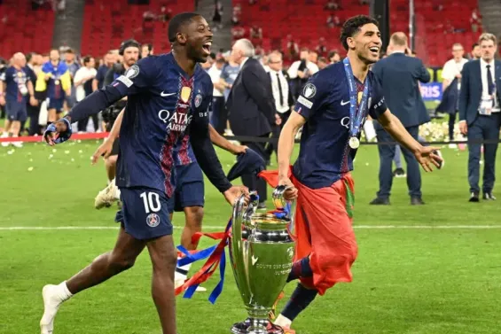 Achraf Hakimi and Ousmane Dembélé with the UEFA Champions League trophy / Photo: Angelika Warmuth - Reuters